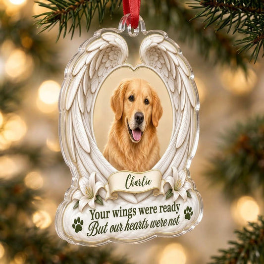 Clear acrylic angel wings ornament with a circular dog photo, white lilies, a dark green paw print, and a name banner.