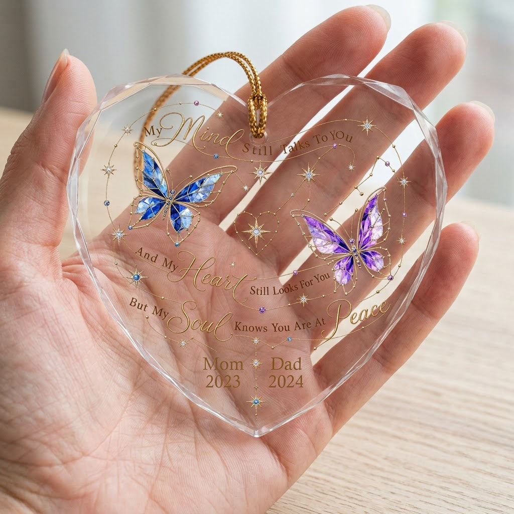 Heart-shaped glass ornament with blue and purple stained-glass butterflies, gold swirls, and memorial text.