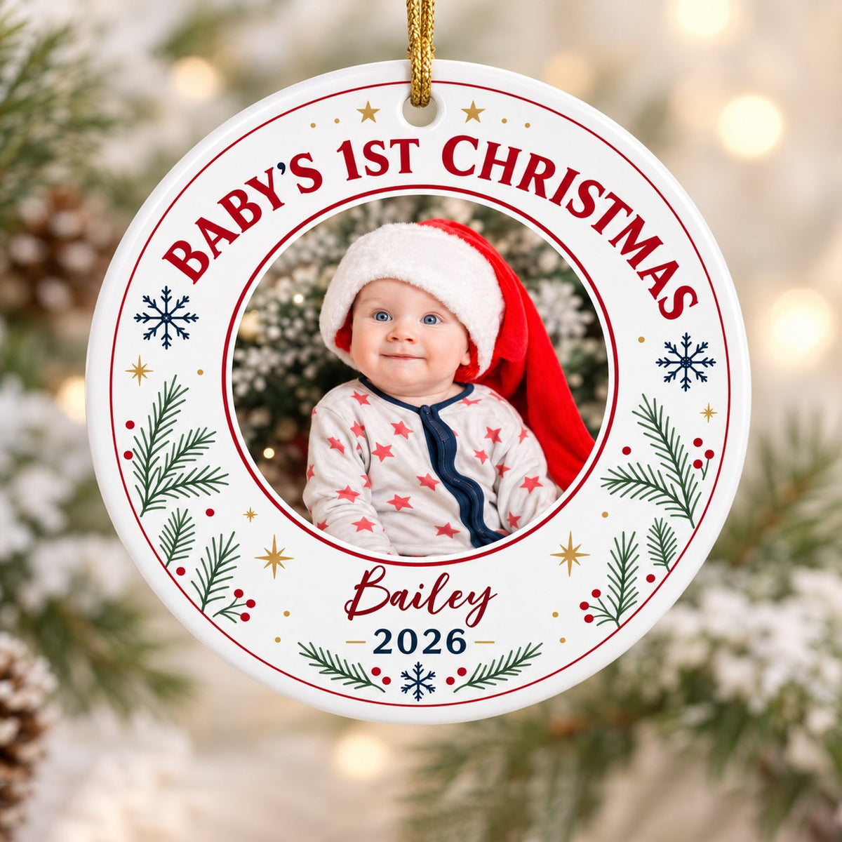 Round ceramic ornament with 'BABY'S 1ST CHRISTMAS', pine sprigs, snowflakes, gold stars, red rings, and a photo frame