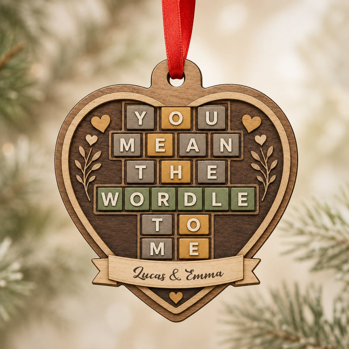 Heart-shaped wood ornament with Wordle-style tiles reading You Mean The Wordle To Me and names on a bottom banner.