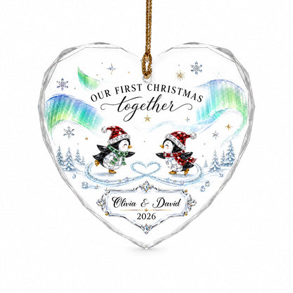 Heart glass ornament with two ice-skating penguins under green and blue aurora with names and date.