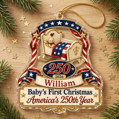 Acrylic ornament with baby crib, teddy bear, patriotic ribbon, and 'Baby's First Christmas', personalized with name and 