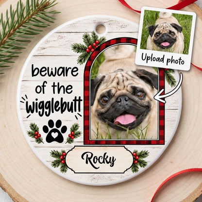 Round ceramic ornament with buffalo plaid photo frame, paw-heart, pine sprigs, and 'beware of the Wigglebutt'.