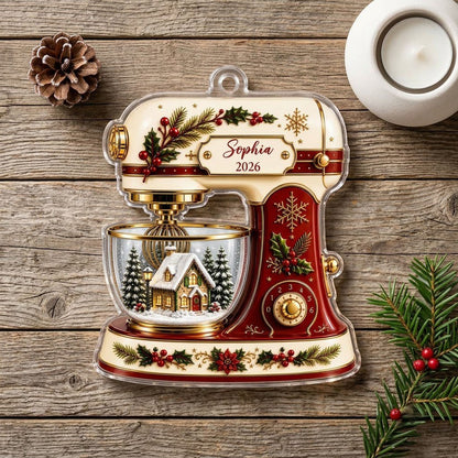 Stand mixer-shaped acrylic ornament with holly, gold snowflakes, and a snowy cottage scene in a glass bowl.