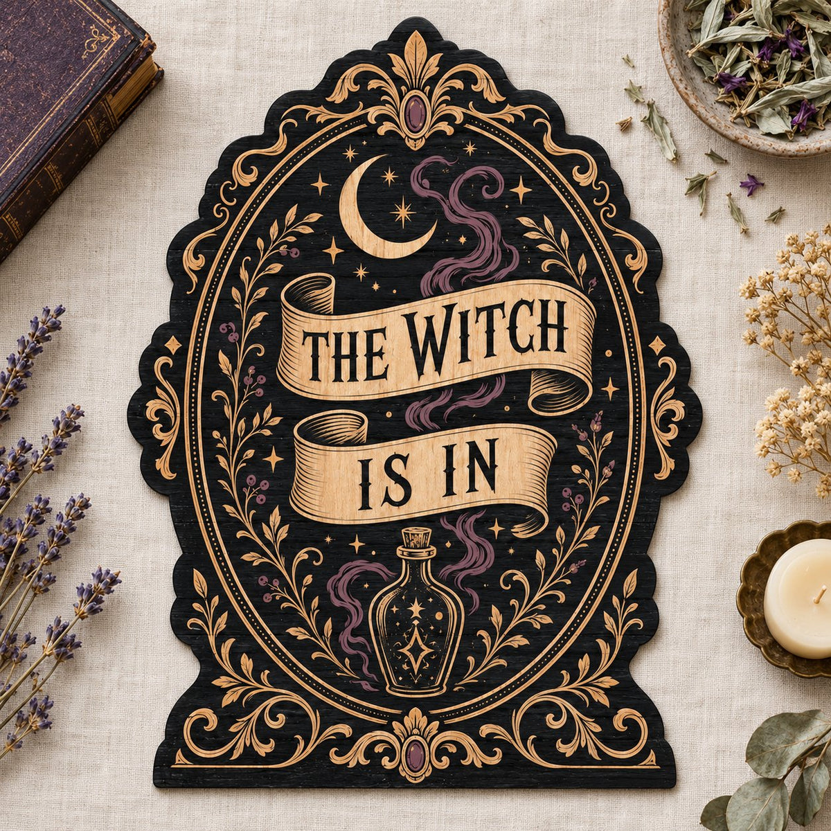 Gothic plaque sign reading "THE WITCH IS IN" with crescent moon, stars, purple smoke, potion bottle and ornate filigree 