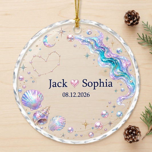 Round glass ornament with iridescent seashells, pearls, crescent moon, and a heart constellation with names and date.