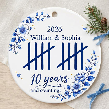 White round ceramic ornament with blue florals, tally marks, and 'years and counting!' plus names and year