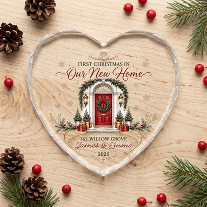 Heart-shaped glass ornament with a red front door, wreath, garland, lanterns, gift boxes, and gold snowflakes.