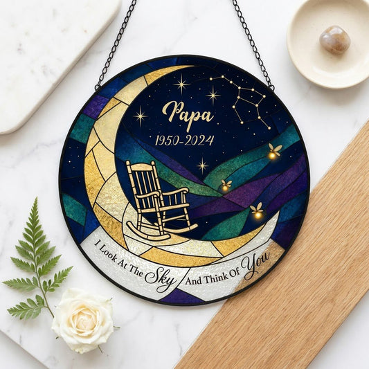 Round stained-glass suncatcher with a crescent moon, rocking chair, fireflies and a memorial banner.