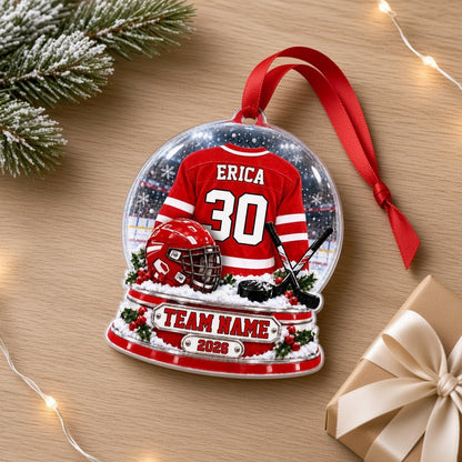 Acrylic snow globe ornament with red hockey jersey, helmet, crossed sticks, puck, holly and a silver name plaque.