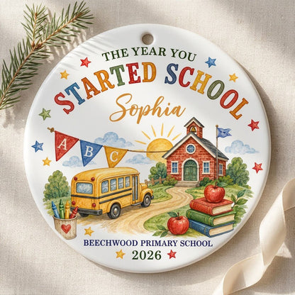 Round ceramic ornament with watercolor school bus, red brick schoolhouse, ABC bunting, books, apples, and colorful stars