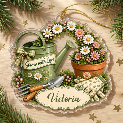 Green watering can with bow, garden tools, and floral pot with ‘Grow with Love’ and a name on a clear acrylic ornament.