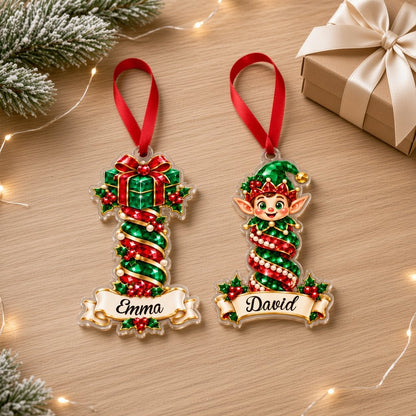 Acrylic ornament with green gift box and smiling elf, jeweled spiral columns, holly, and a name banner.