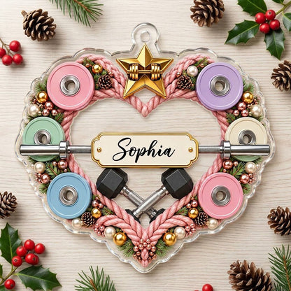 Clear acrylic heart ornament with pink rope wreath, pastel plates, barbell, crossed dumbbells, and a name plaque.