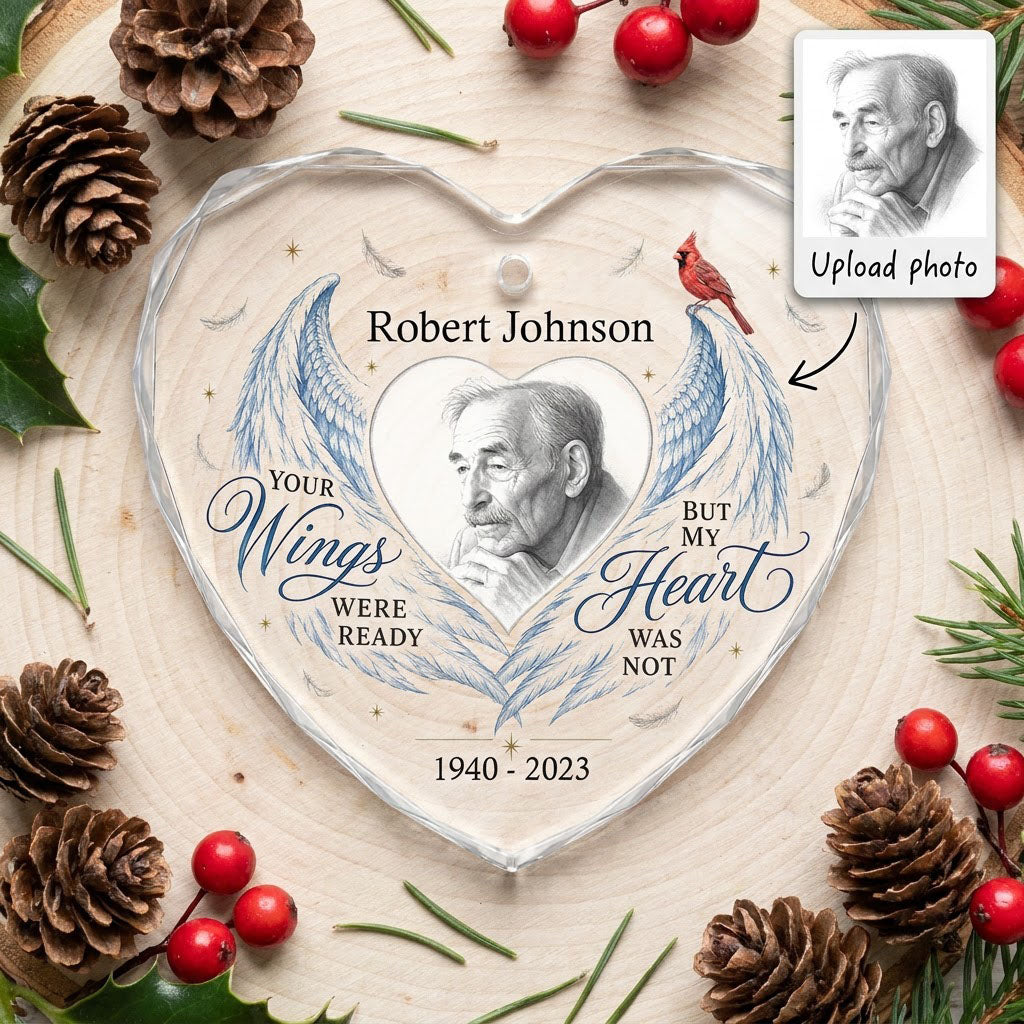 Heart-shaped glass ornament with blue angel wings, red cardinal, and a memorial quote with name and years.