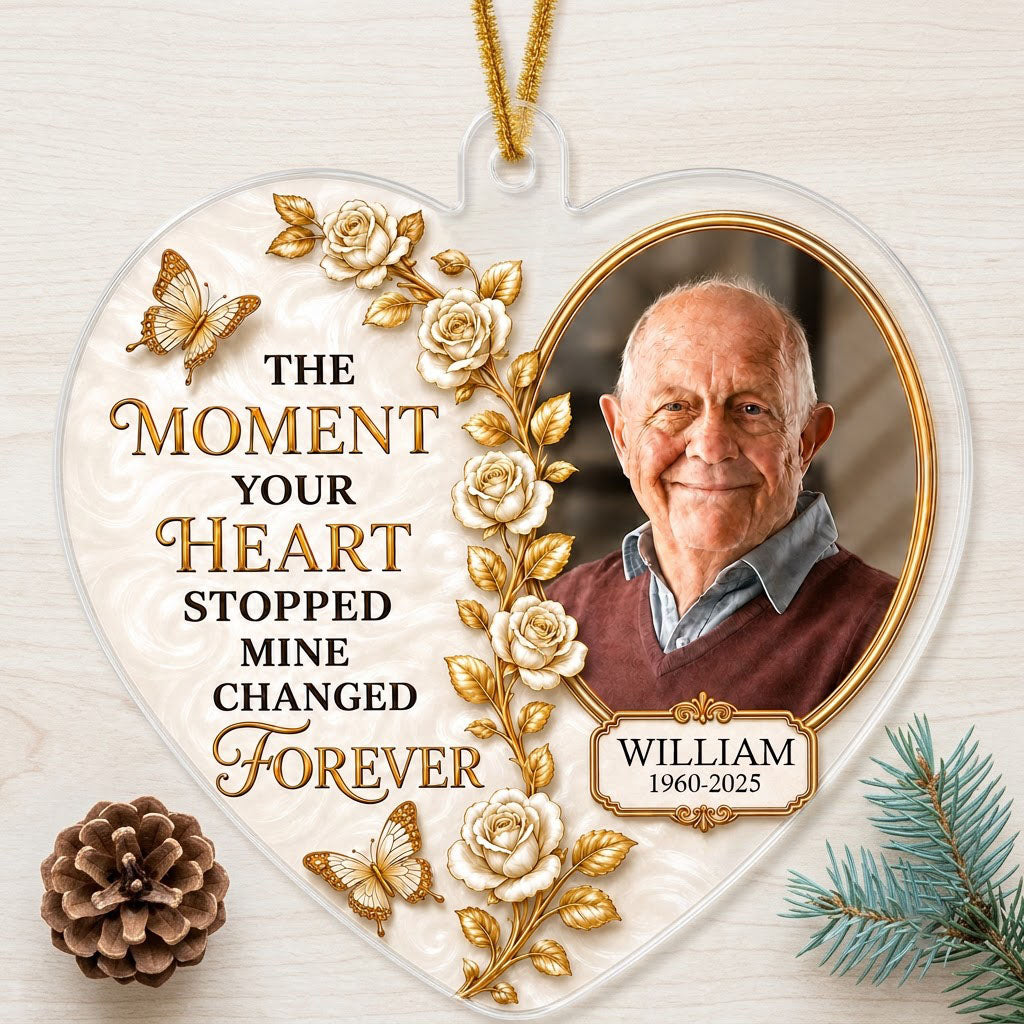 Heart-shaped acrylic ornament with a photo in a gold oval frame, white roses, gold butterflies, and a name plaque.