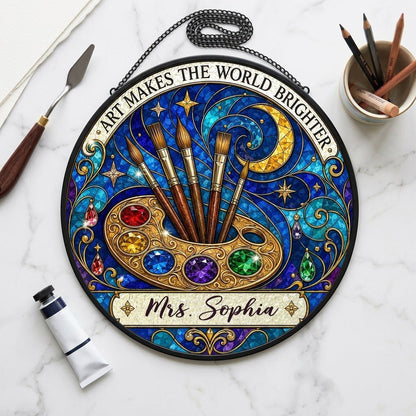 Round stained-glass suncatcher with golden palette, five brushes, moon, and 'Art Makes the World Brighter'.