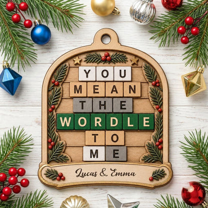 Arch wood ornament with “You Mean The Wordle To Me” letter tiles, evergreen sprigs with red berries, gold stars, and cou