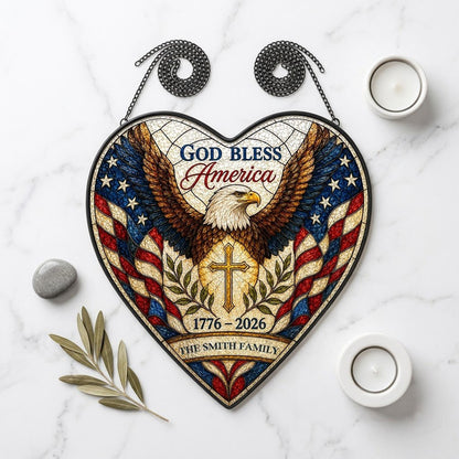 Heart-shaped stained glass suncatcher with a bald eagle over a golden cross and American flag border.