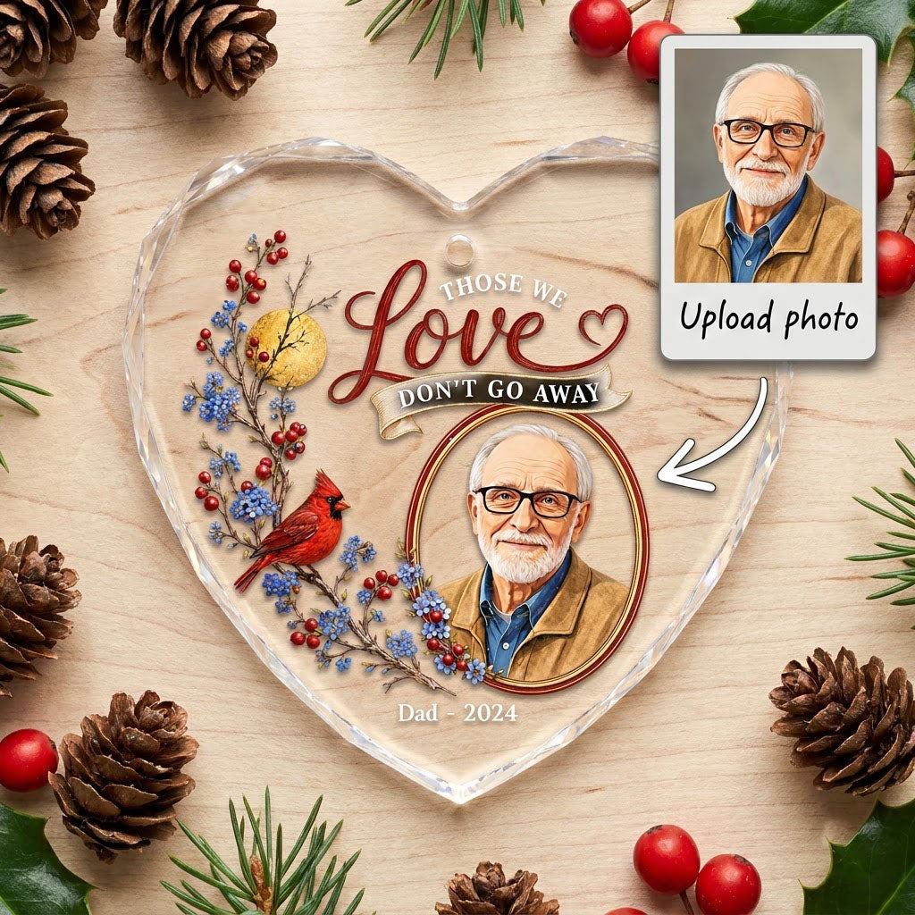 Heart-shaped glass ornament with a red cardinal, golden moon, photo frame and the quote 'THOSE WE Love DON'T GO AWAY'.