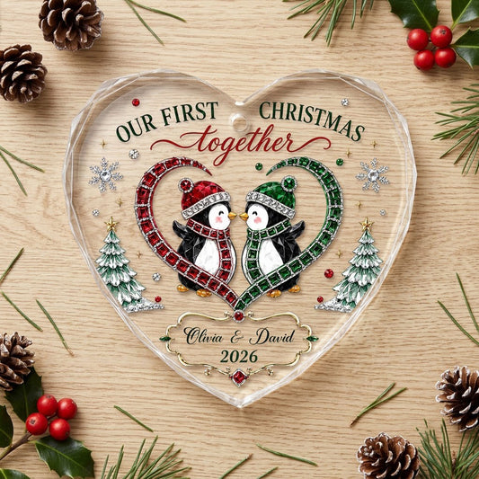 Heart-shaped stained glass suncatcher with two penguins in red and green scarves, jeweled trees, and silver snowflakes