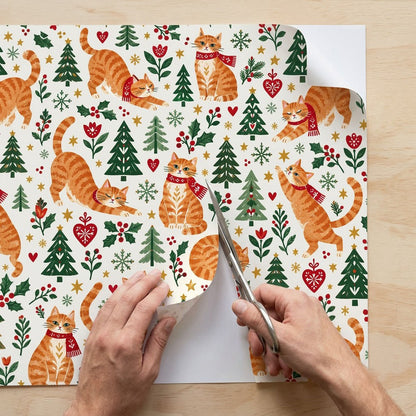 Cream wrapping paper with ginger tabby cats in red scarves, pine trees, hearts, berries, stars, and snowflakes.