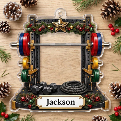 A squat rack-shaped acrylic ornament with garland, barbell, dumbbells, and a photo cutout above a name plaque.
