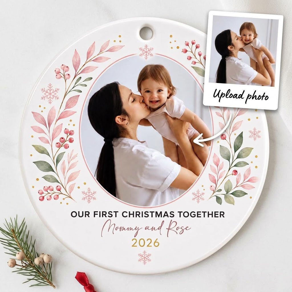 Round ceramic ornament with a photo frame, pink-green botanical wreath, and 'OUR FIRST CHRISTMAS TOGETHER' text.