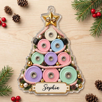 Acrylic Christmas tree ornament of stacked pastel weight plates with a gold star dumbbell and a cream name banner.
