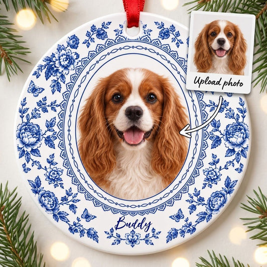 Round white ceramic ornament with blue Delft floral and butterfly pattern around an oval dog photo and name.