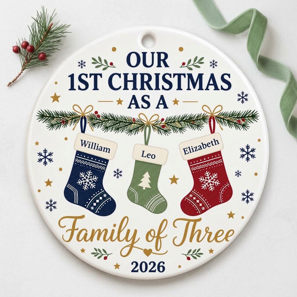 Round white ceramic ornament with garland, three stockings, and 'OUR 1ST CHRISTMAS AS A Family of Three 2026' text with 