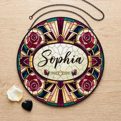 Round stained glass-style suncatcher with red and pink roses, a cream oval name panel, and black leaded lines.