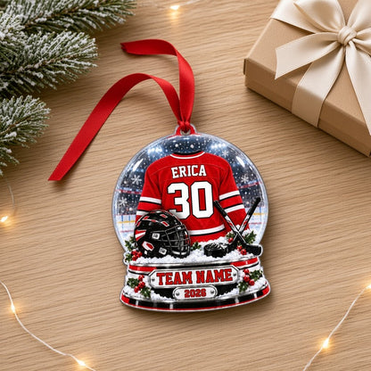 Snow globe acrylic ornament with red and white hockey jersey, black helmet and puck, and a snowy rink backdrop.