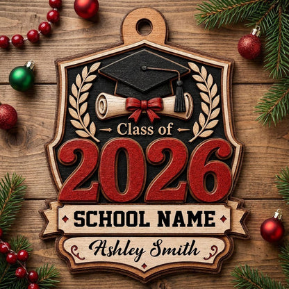 Shield-shaped wood ornament with Class of 2026, cap, diploma, laurel branches, and a personalized name and school