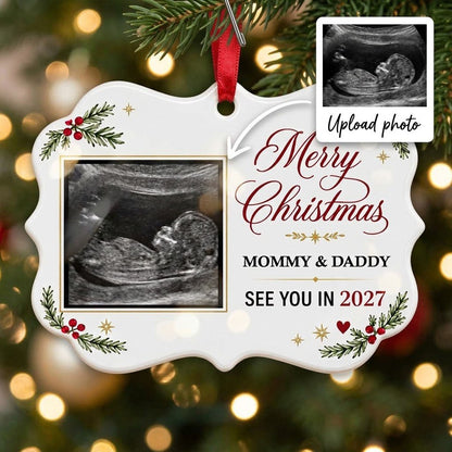 Round ceramic ornament with ultrasound photo, pine branches with red berries, gold starbursts and a red heart icon.