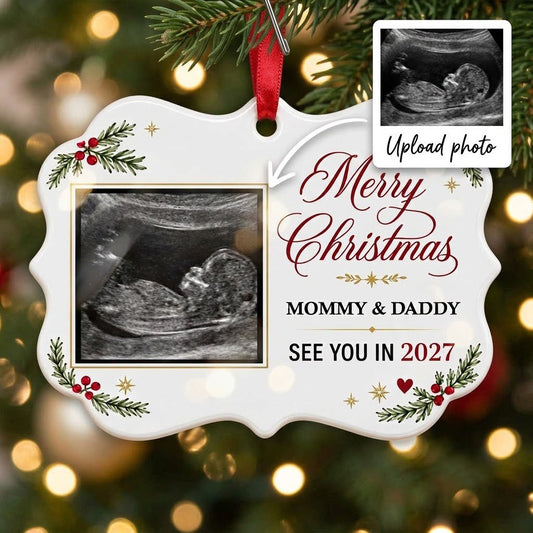 Round ceramic ornament with ultrasound photo, pine branches with red berries, gold starbursts and a red heart icon.
