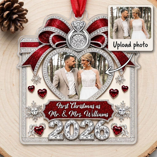 Acrylic ornament with red glitter bow, engagement ring, heart photo frame, snowflakes, and Mr. & Mrs. name and year.