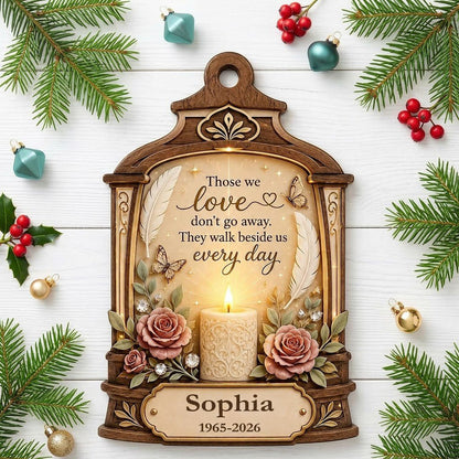 Arched wood-look ornament with lit white candle, two pink roses, butterflies, feathers, and a memorial quote.