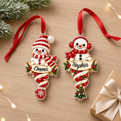 Custom-cut acrylic snowman ornaments with red scarves and scroll banners personalized with a child's name.