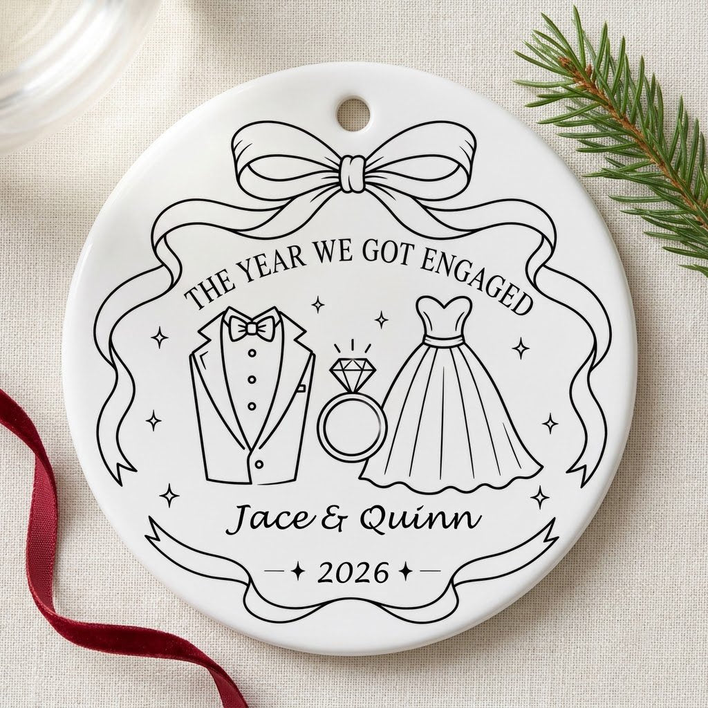 Round white ceramic ornament with black line art of bow, tuxedo, ring, dress, and THE YEAR WE GOT ENGAGED banner.