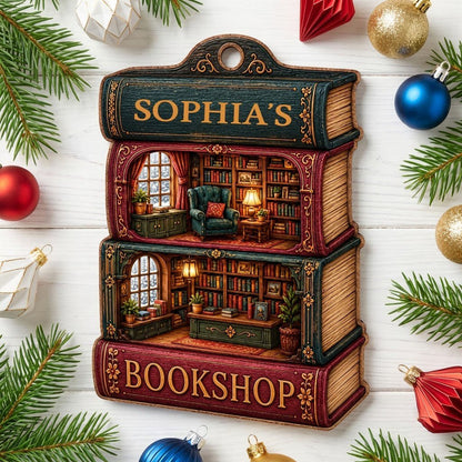Custom-cut ornament of stacked books showing cozy bookshop rooms, BOOKSHOP text, and a personalized name.