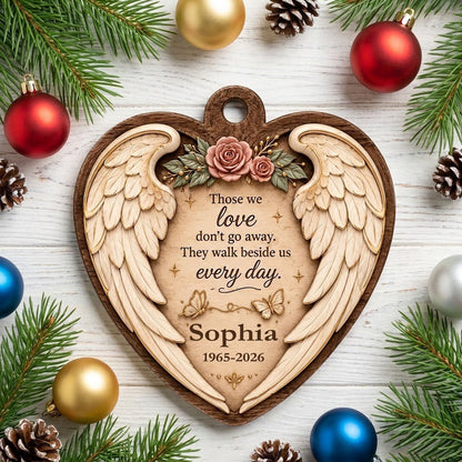 Heart-shaped wood ornament with angel wings, pink roses, butterflies, and a memorial quote with name and dates.