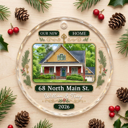 Round glass ornament with watercolor house, green and gold banners, gold key, pine branches, and address and year plaque