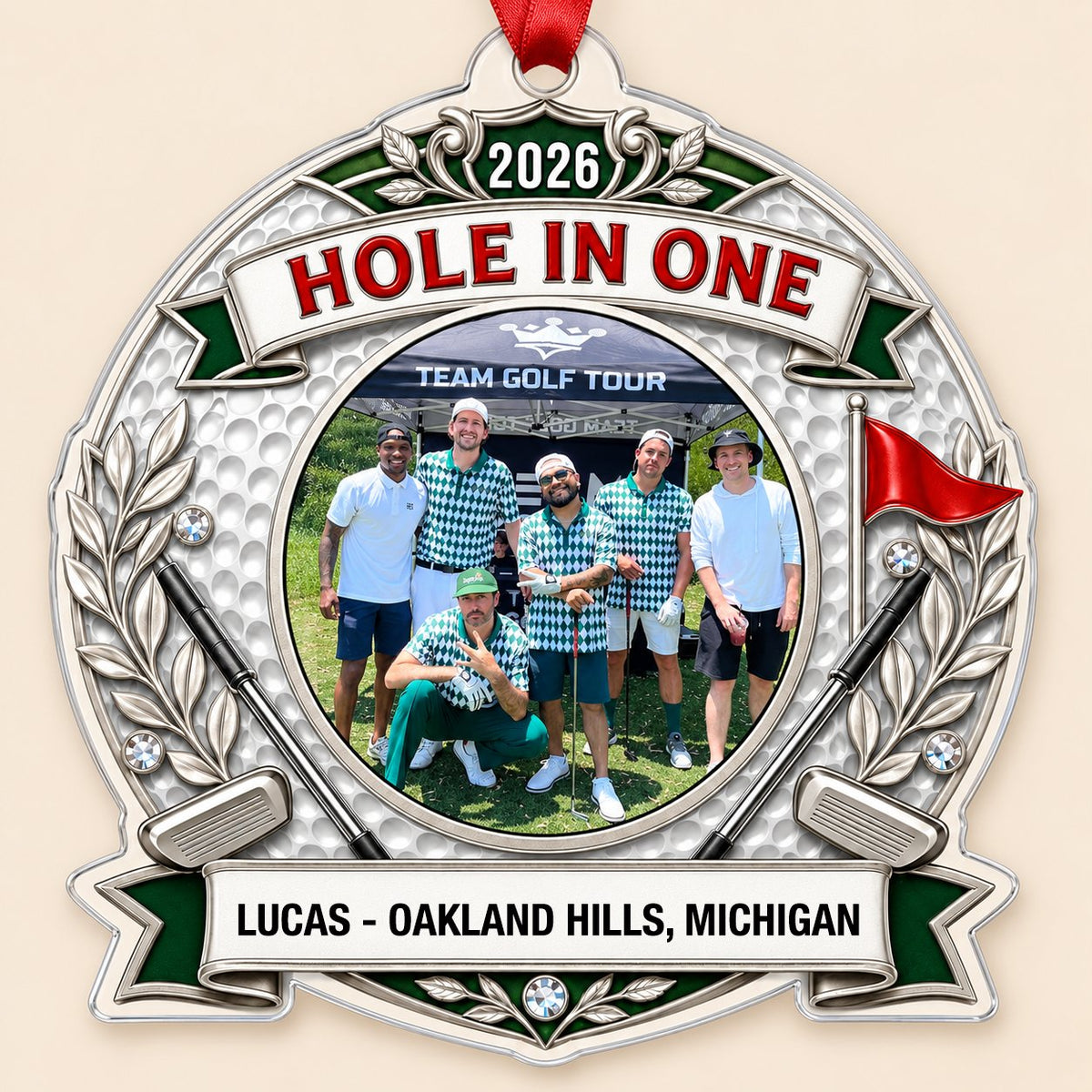 Silver trophy-style golf ornament with laurel branches, crossed clubs, red flag, 2026 and HOLE IN ONE, plus a circular p