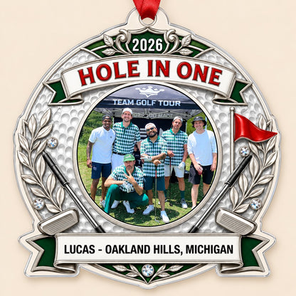 Silver trophy-style golf ornament with laurel branches, crossed clubs, red flag, 2026 and HOLE IN ONE, plus a circular p