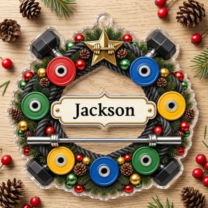 Acrylic ornament shaped around a gym wreath with dumbbells, bumper plates, barbell, and a name banner.