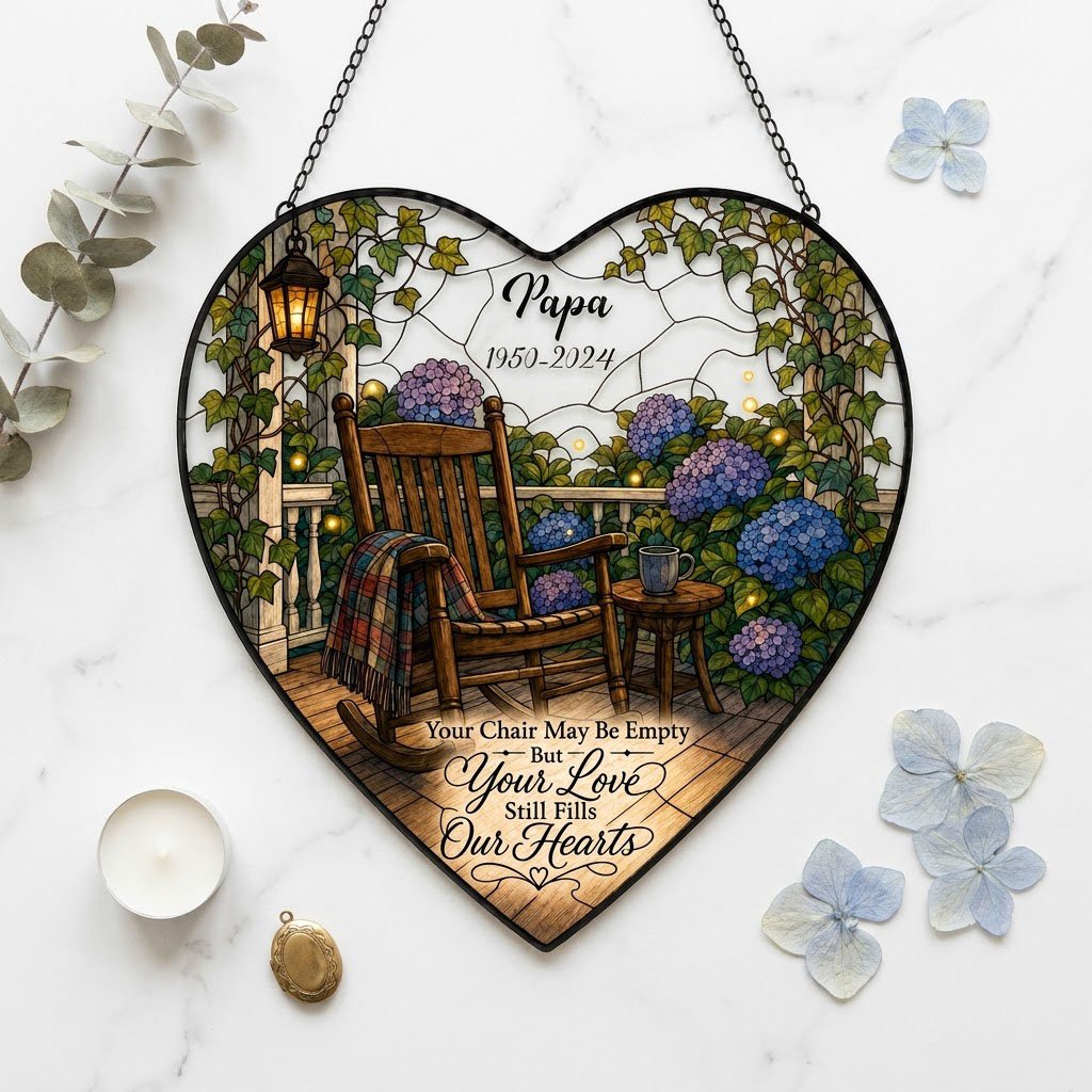 Heart stained glass suncatcher with empty porch rocking chair, lantern, ivy, and purple and blue hydrangea bushes.