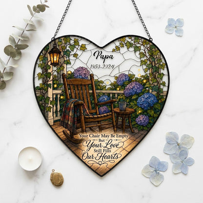 Heart stained glass suncatcher with empty porch rocking chair, lantern, ivy, and purple and blue hydrangea bushes.