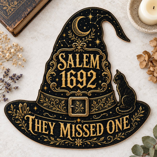 Witch hat-shaped wooden sign with 'SALEM 1692 THEY MISSED ONE', crescent moon, stars, filigree, and a black cat on the b