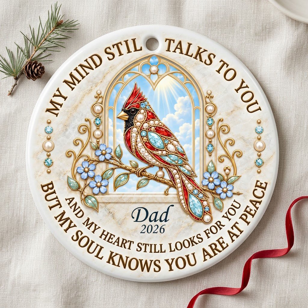 Round ceramic ornament with a red cardinal by a gold arched window, blue flowers, pearls, and a faux marble border.
